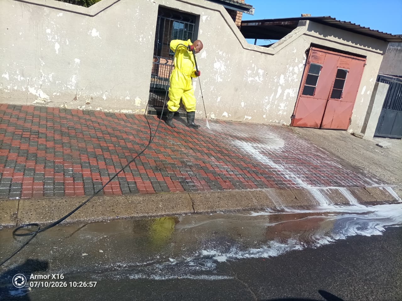 Sejo operator in PPE high-pressure washing a commercial forecourt